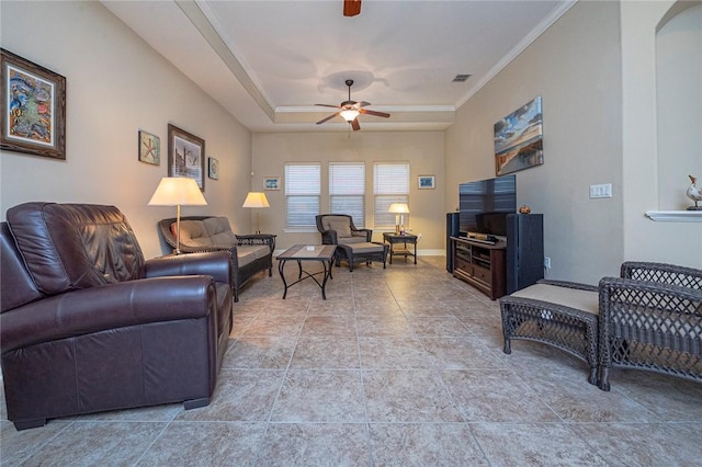 living area featuring a tray ceiling, crown molding, ceiling fan, tile patterned flooring, and baseboards