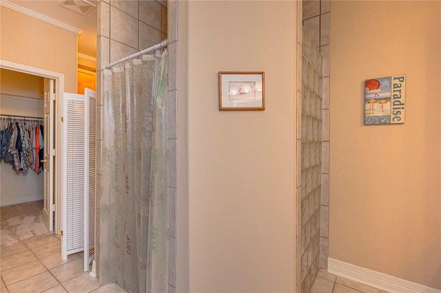 bathroom featuring tile patterned flooring, visible vents, baseboards, ornamental molding, and a tile shower