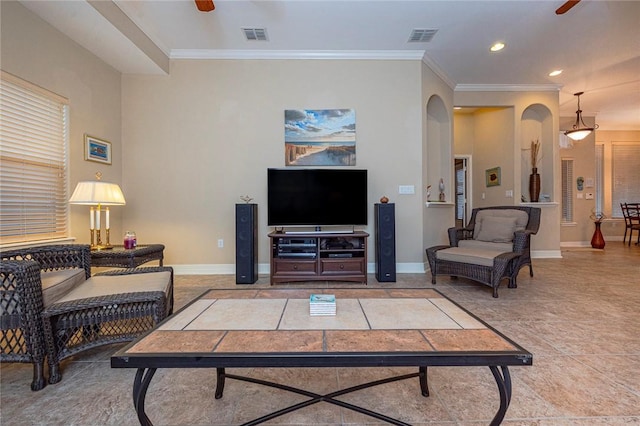 living room with arched walkways, a ceiling fan, visible vents, baseboards, and ornamental molding