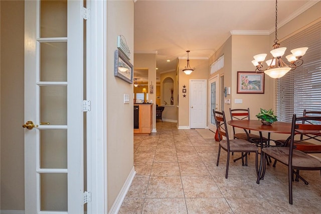 dining space featuring baseboards, arched walkways, crown molding, and light tile patterned flooring