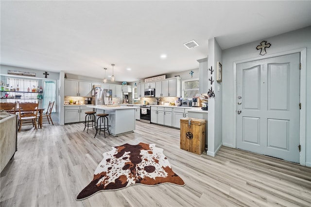 kitchen featuring a breakfast bar, a kitchen island, hanging light fixtures, and plenty of natural light