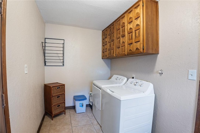 laundry room featuring light tile patterned floors, washing machine and dryer, cabinets, and a textured ceiling