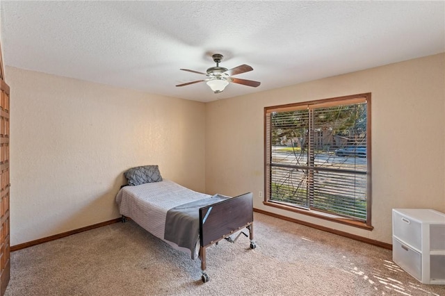 carpeted bedroom featuring ceiling fan and a textured ceiling