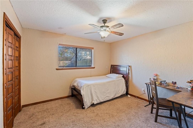 carpeted bedroom featuring ceiling fan and a textured ceiling