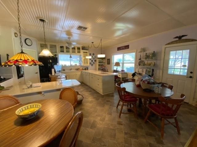 25006 Tuckers Trl, Mathis, TX 78368 - kitchen with stone finish flooring, freestanding refrigerator, a peninsula, white cabinetry, and decorative light fixtures