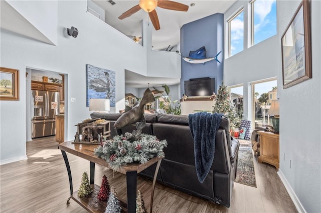 living room featuring a high ceiling, light wood-type flooring, and ceiling fan