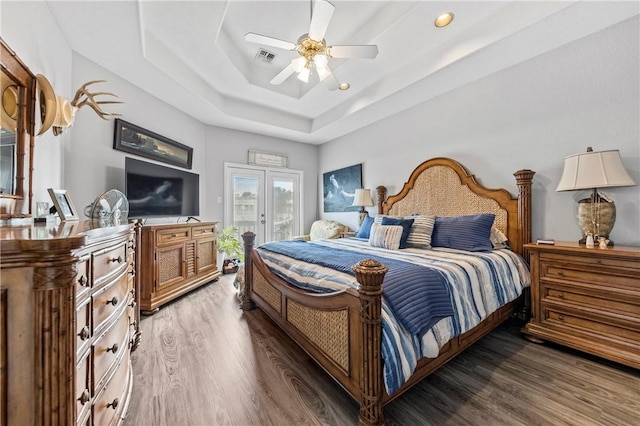 bedroom with a raised ceiling, ceiling fan, french doors, and dark wood-type flooring