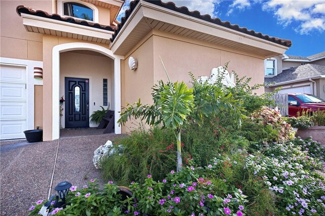 15362 Isabella Ct, Corpus Christi, TX 78418 - doorway to property with stucco siding, a tiled roof, and a garage