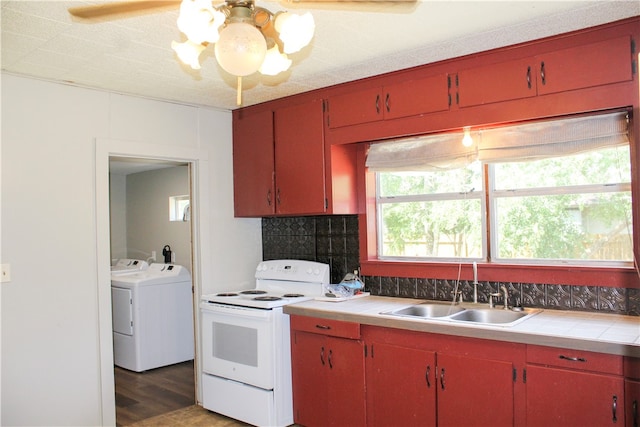 kitchen featuring sink, white range with electric stovetop, ceiling fan, dark hardwood / wood-style floors, and washing machine and clothes dryer