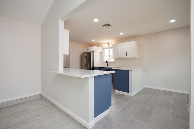 kitchen featuring white cabinets, stainless steel fridge, sink, and kitchen peninsula