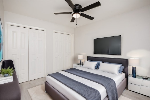 bedroom featuring multiple closets, light wood-type flooring, and ceiling fan