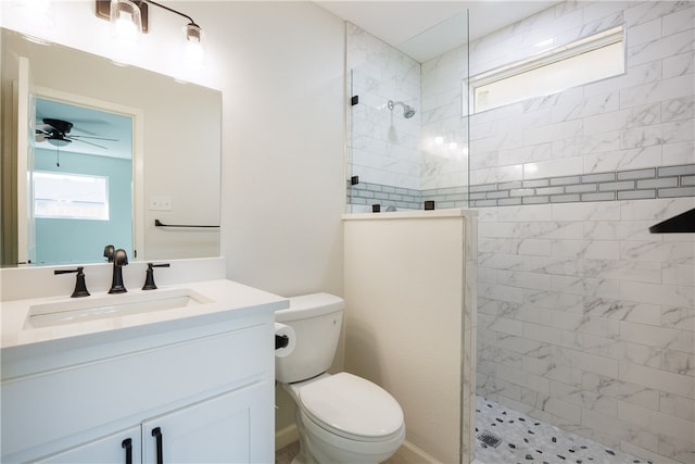 bathroom featuring toilet, ceiling fan, vanity, and a tile shower