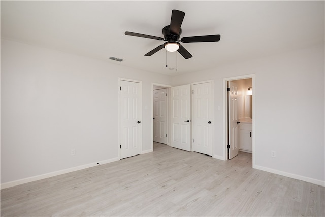 unfurnished bedroom featuring light hardwood / wood-style floors, two closets, ceiling fan, and ensuite bath