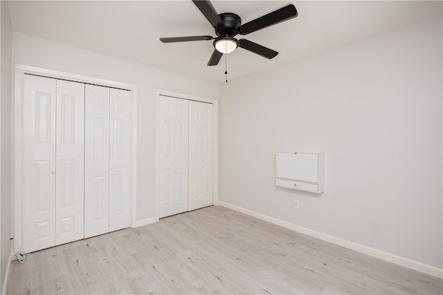 unfurnished bedroom with ceiling fan, multiple closets, and light wood-type flooring