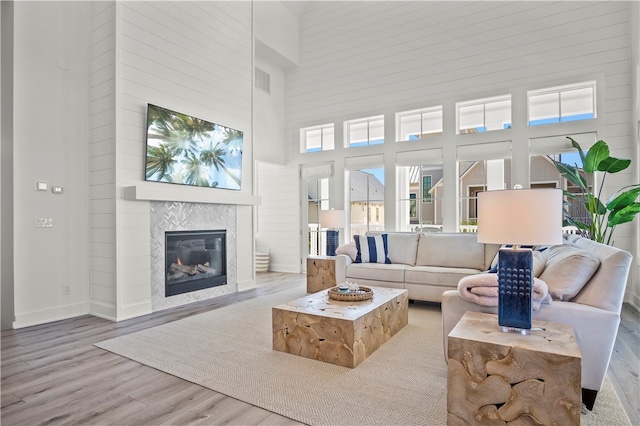 living room featuring a fireplace, light hardwood / wood-style flooring, and a high ceiling