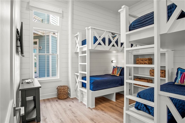 bedroom featuring wood walls, wood-type flooring, and crown molding