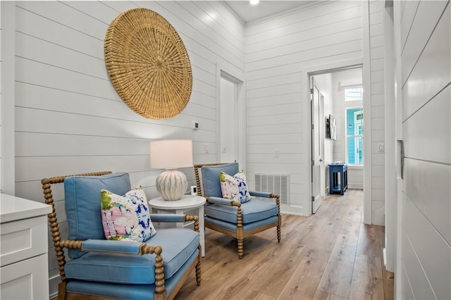 living area with a high ceiling, wood walls, and light hardwood / wood-style flooring