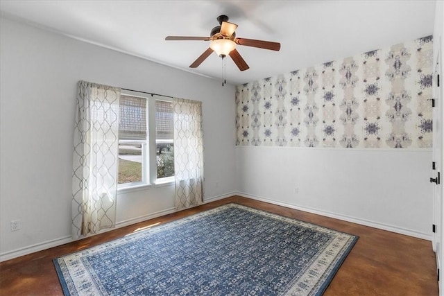 spare room with ceiling fan and baseboards