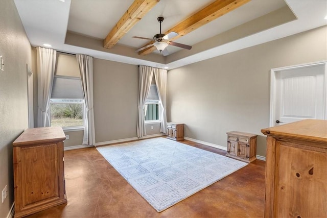 interior space featuring finished concrete flooring, baseboards, a ceiling fan, a tray ceiling, and beam ceiling