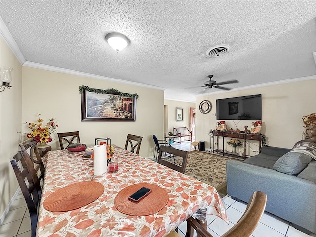 tiled dining room featuring ceiling fan, ornamental molding, and a textured ceiling