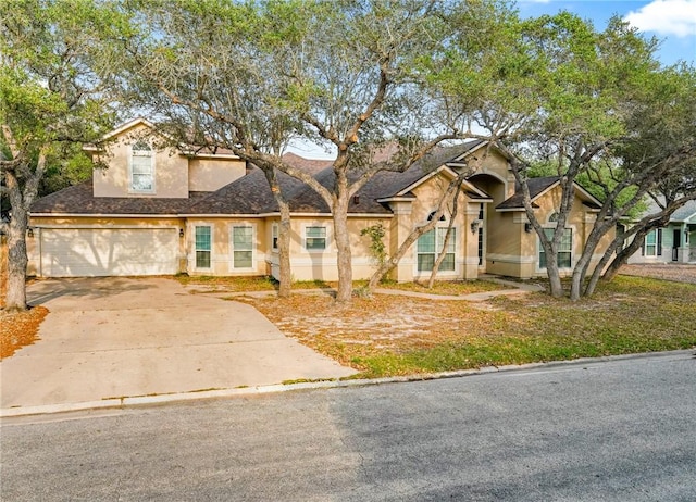 view of front of home with a garage, stucco siding, a shingled roof, and concrete driveway