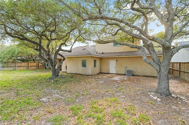 back of house with fence, central air condition unit, and stucco siding