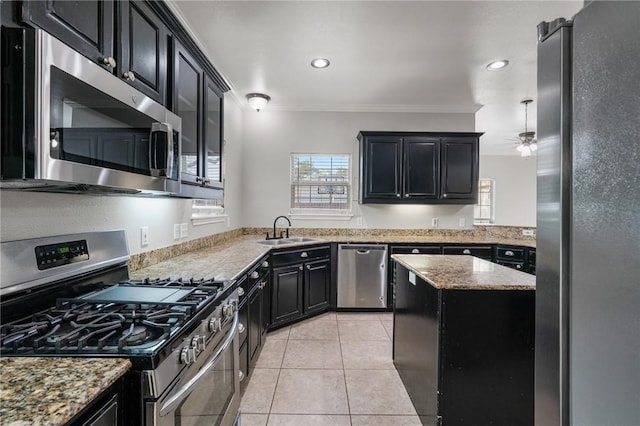 kitchen featuring dark cabinets, appliances with stainless steel finishes, ornamental molding, and a sink