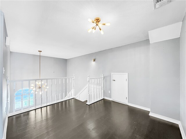 unfurnished room featuring a chandelier and dark hardwood / wood-style floors