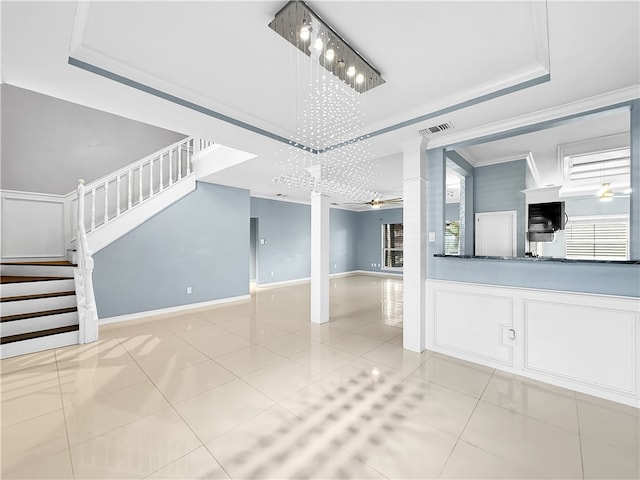 unfurnished living room featuring a raised ceiling, crown molding, light tile patterned floors, and ceiling fan with notable chandelier