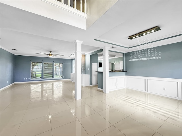 unfurnished room with ceiling fan with notable chandelier, light tile patterned floors, crown molding, and decorative columns