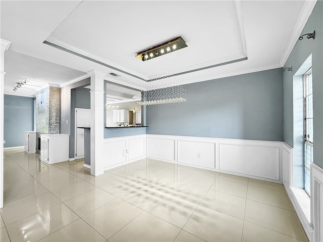 tiled spare room featuring a notable chandelier, a raised ceiling, and ornamental molding