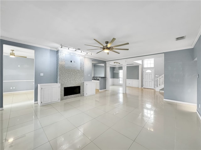 unfurnished living room with a large fireplace, ceiling fan, crown molding, and light tile patterned flooring