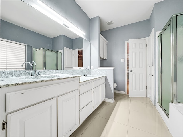 bathroom with tile patterned floors, a shower with door, vanity, and toilet