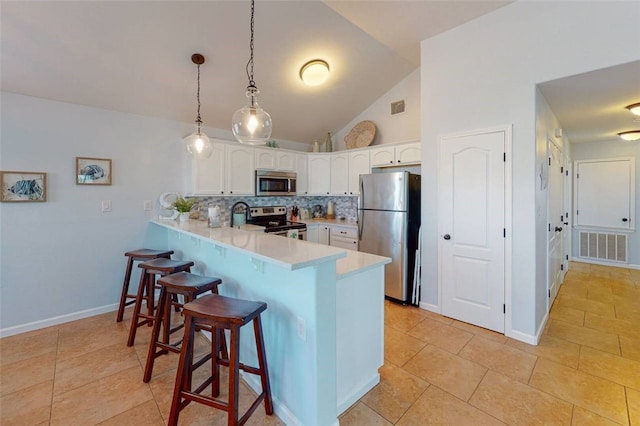 kitchen featuring hanging light fixtures, kitchen peninsula, white cabinets, and appliances with stainless steel finishes