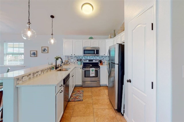 kitchen featuring decorative light fixtures, kitchen peninsula, white cabinets, and appliances with stainless steel finishes