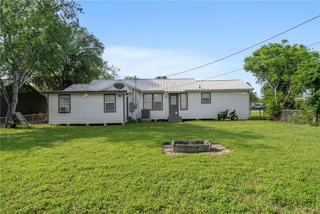 back of house featuring a fire pit, central air condition unit, fence, entry steps, and a lawn