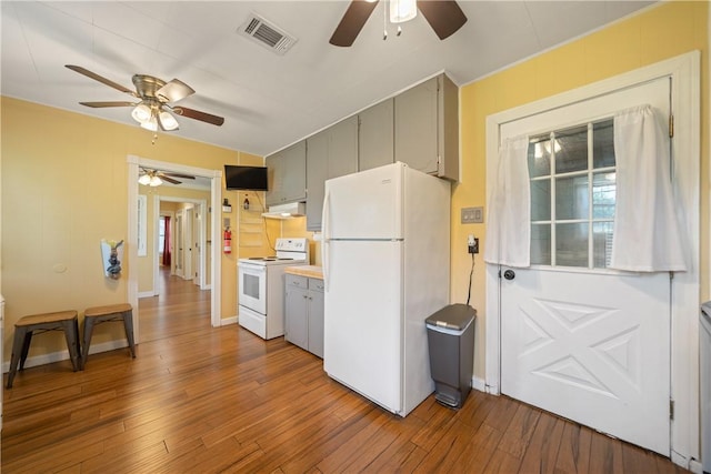 kitchen with hardwood / wood-style flooring, visible vents, a ceiling fan, and white appliances