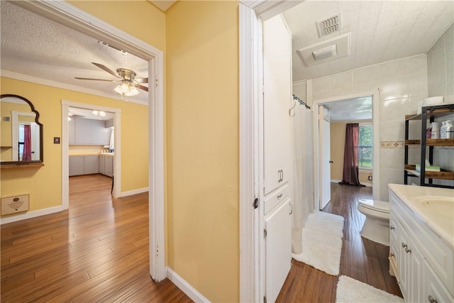 full bath with vanity, toilet, ceiling fan, visible vents, and wood finished floors