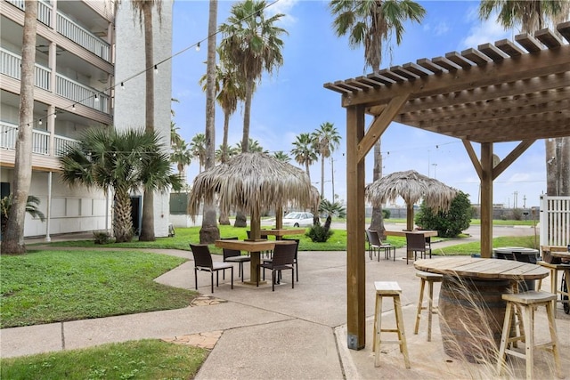 view of property's community with a lawn, a pergola, outdoor dining area, and a patio area