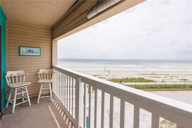 balcony featuring a view of the beach and a water view