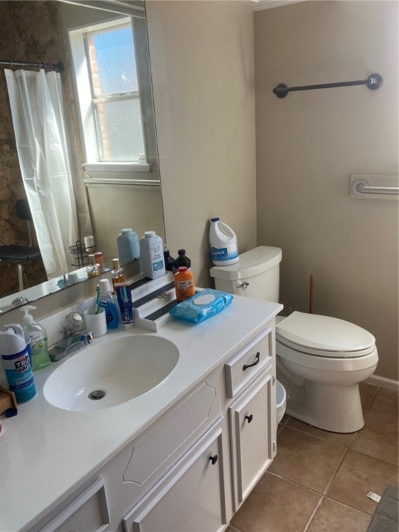 bathroom with toilet, vanity, and tile patterned flooring