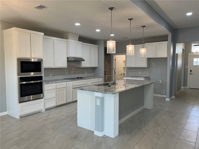 kitchen with white cabinetry, sink, light stone countertops, a kitchen island with sink, and appliances with stainless steel finishes