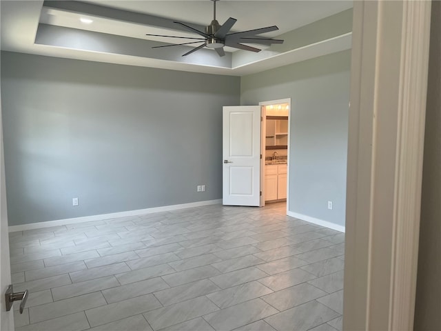 unfurnished room featuring ceiling fan, a raised ceiling, light tile patterned floors, and sink