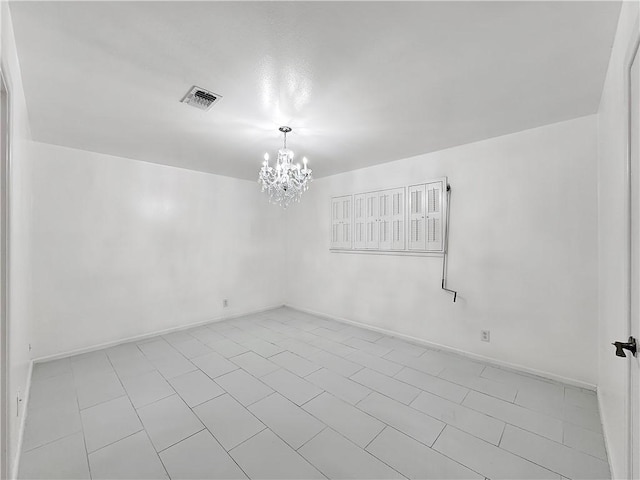 tiled empty room with baseboards, visible vents, and an inviting chandelier