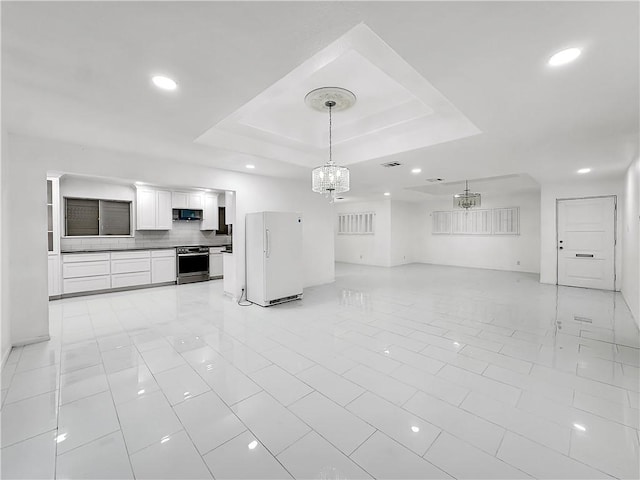 unfurnished living room featuring a tray ceiling, an inviting chandelier, recessed lighting, and light tile patterned floors