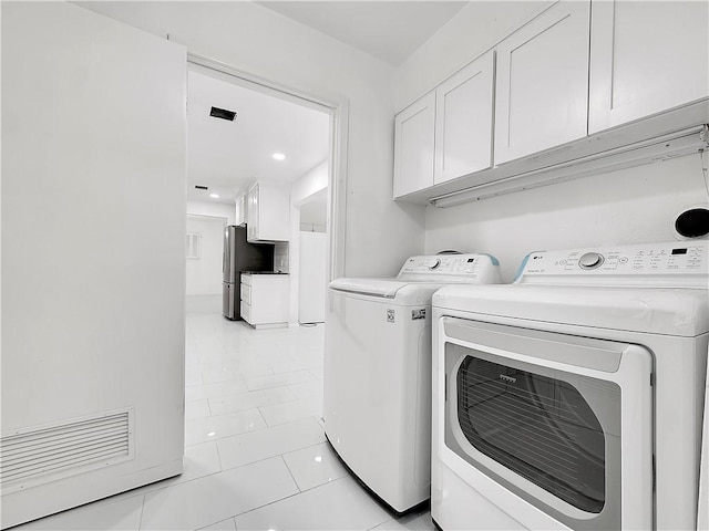 washroom featuring washer and clothes dryer, light tile patterned floors, and cabinet space