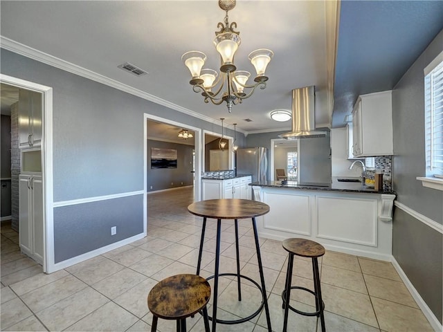 kitchen with white cabinets, stainless steel fridge, island exhaust hood, and crown molding