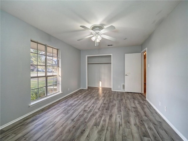 unfurnished bedroom featuring hardwood / wood-style floors, ceiling fan, and a closet