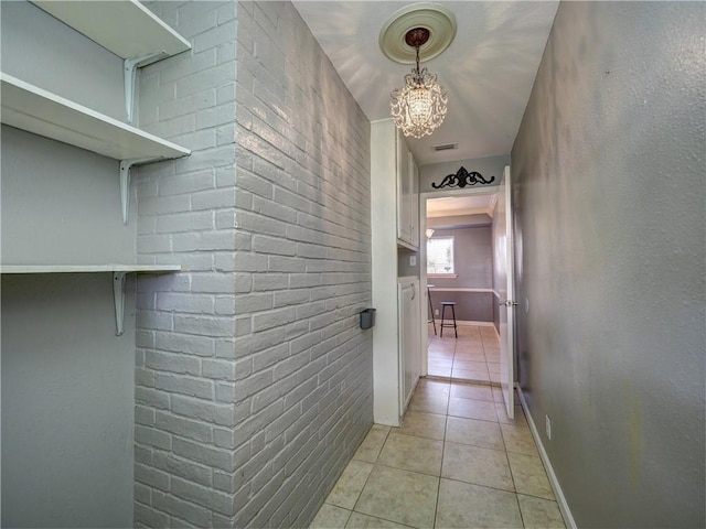 corridor with light tile patterned flooring and a chandelier