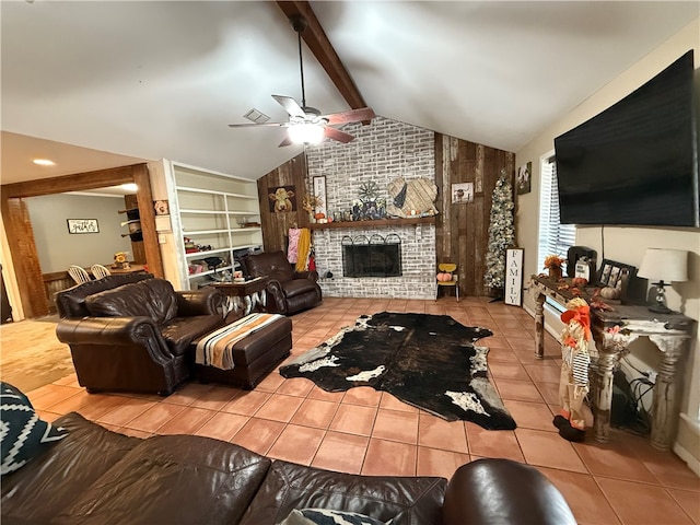 living room featuring lofted ceiling with beams, ceiling fan, built in features, a fireplace, and light tile patterned flooring